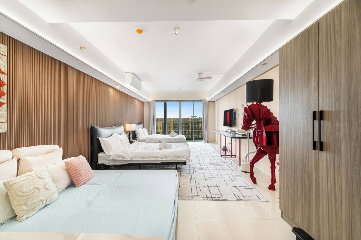 Ein modernes Hotelzimmer mit zwei Betten, einer Sitzecke, einem Fernseher und einem großen Fenster mit Blick auf die Stadt.