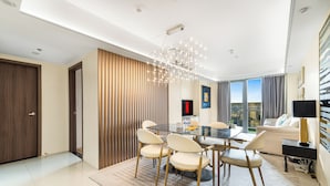 A modern dining area with a glass table, white chairs, and a chandelier. - Spacious & High-Floor Hotel near City of Dreams, Airport, Okada, and Solaire Casino (Parañaque)
