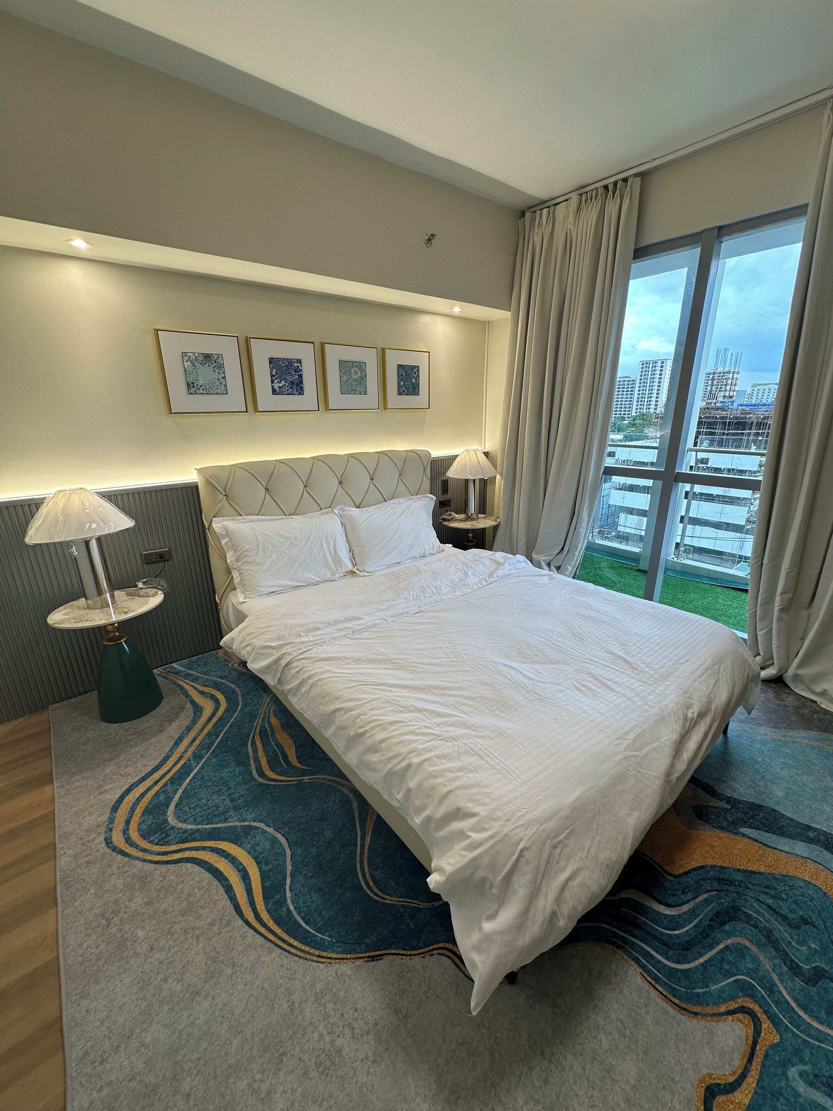 A hotel room with a large bed, a view of the city, and a modern design.