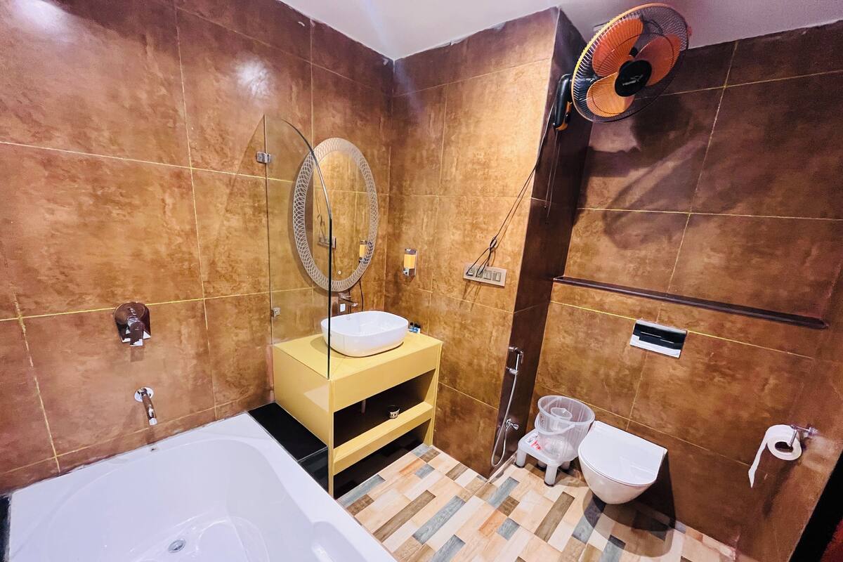A bathroom with a bathtub, a sink with a mirror, a toilet, and a shower area.