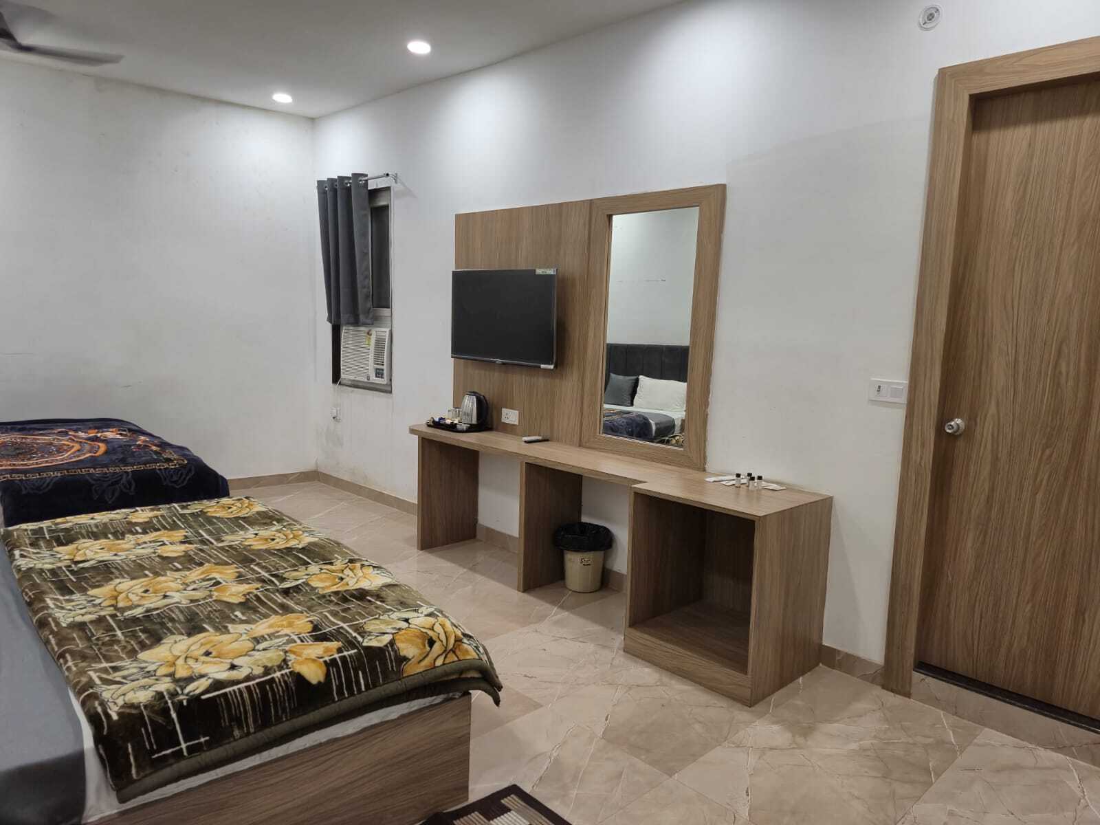 Ein Schlafzimmer mit Bett, Schreibtisch, Spiegel, Fernseher und einer Tür.