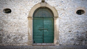 A stone building with a green arched door and two small windows. - Tenuta dell'inviolata (Velletri)