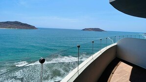 A balcony with a view of the sea and distant islands.