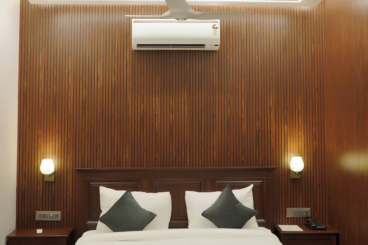 A bedroom with a wooden paneled wall, a large bed with two pillows, a ceiling fan, and a chandelier.