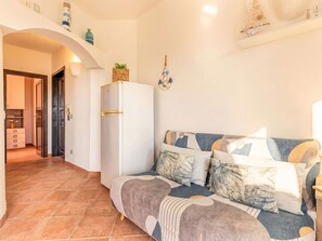 A modern living room with a sofa, a white refrigerator, and a tiled floor. - Angela House by Interhome (Castelsardo)