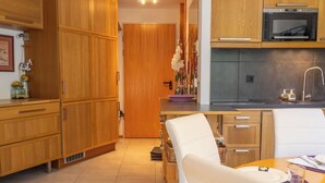Una cocina moderna con armarios de madera, un comedor con una silla blanca y un horno empotrado sobre la encimera.