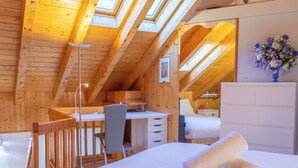 Un dormitorio acogedor en el ático con techo de madera, un escritorio, una silla y una cama con toallas enrolladas.