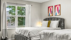 A bedroom with two beds, a window with curtains, and two abstract paintings on the wall. - Modern 4BR Family Friendly Retreat W/ Hot tub (Arvada)