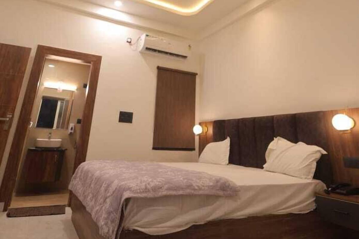 A modern bedroom with a wooden bed, a nightstand, a mirror, and a ceiling light fixture.