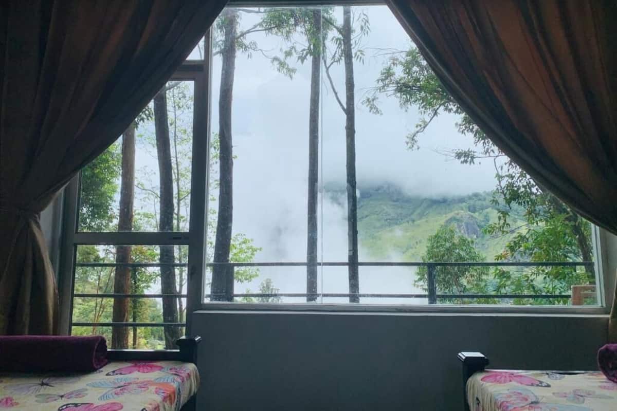 A room with a large window offering a view of a forested landscape.