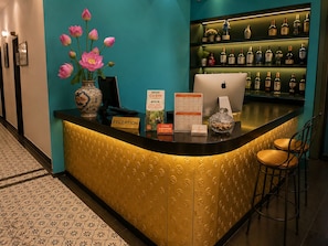 A reception desk with a laptop, a vase of flowers, and a menu board. - The Rice Hotel & Tour - 180 Bui Vien (Ho Chi Minh City)
