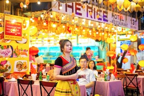 A restaurant with tables covered in checkered tablecloths, a sign indicating it's a hotel restaurant, and hanging lanterns. - The Rice Hotel & Tour - 180 Bui Vien (Ho Chi Minh City)