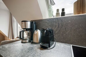 A kitchenette with a coffee maker, a kettle, and a toaster on a granite countertop. - Dünenloft, House Düne Whg. 12 - Dünenlofts (Sylt)