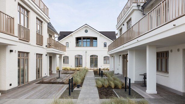 A courtyard with a central pathway, surrounded by buildings with balconies and large windows. - Dünenloft, House Düne Whg. 12 - Dünenlofts (Sylt)