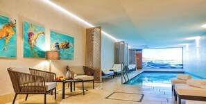 A hotel room with a pool, artwork on the walls, and a view of the sea.