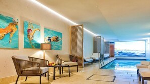 A modern indoor pool area with lounge chairs, a table with fruits, and artwork on the walls. - Dünenloft, House Düne Whg. 12 - Dünenlofts (Sylt)