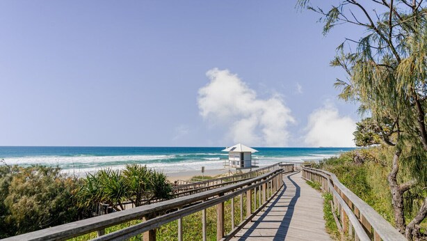 A wooden boardwalk leading to a beach with a lifeguard station.