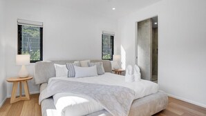 A modern bedroom with a large bed, two bedside tables, and a large mirror.