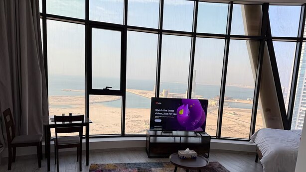 A hotel room with a large window offering a view of a coastal landscape.