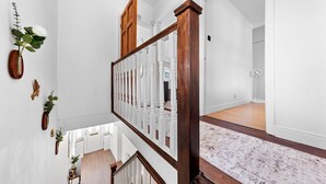 Un interior espacioso y bien iluminado, con techos altos, una escalera de madera y vistas a un comedor.