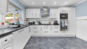 Una cocina moderna con gabinetes blancos, horno integrado y lavavajillas.