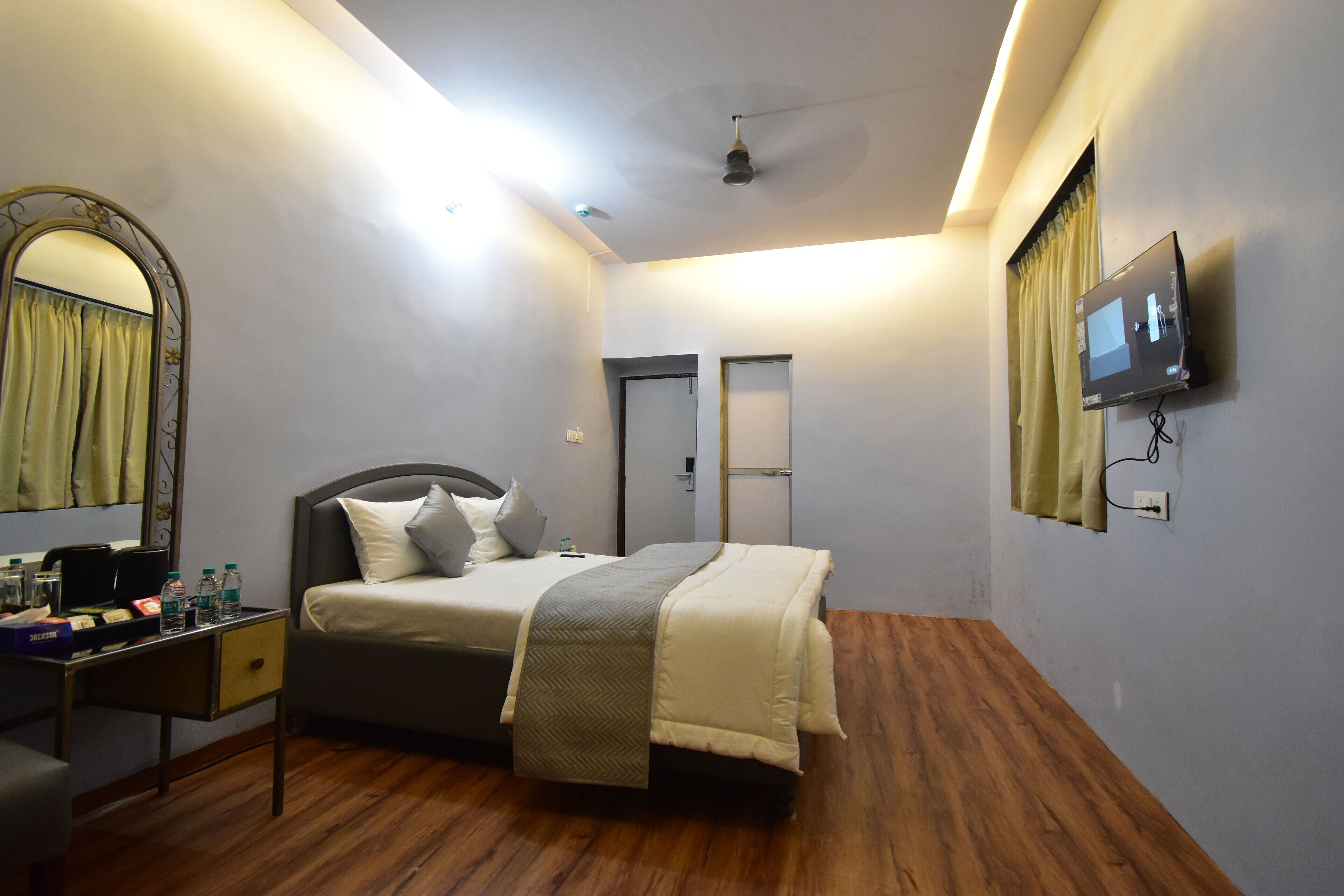 Un dormitorio con cama, escritorio con espejo, televisión y ventilador de techo.