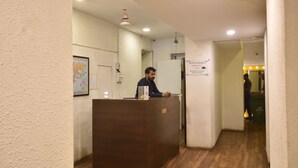 A reception desk in a hotel lobby with a wooden floor and a map on the wall. - Hotel Evergreen  (Mumbai)