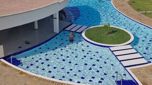 Una piscina dalla forma sinuosa, una piccola isola e vista sul mare.