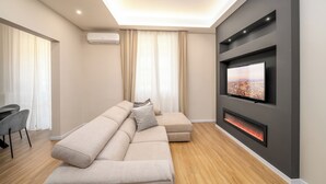 A modern living room with a sectional sofa, a flat-screen TV, a fireplace, and a dining area with a table and chairs.