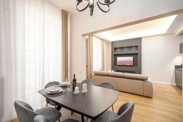 Un soggiorno moderno con zona pranzo, un divano e una TV a parete.