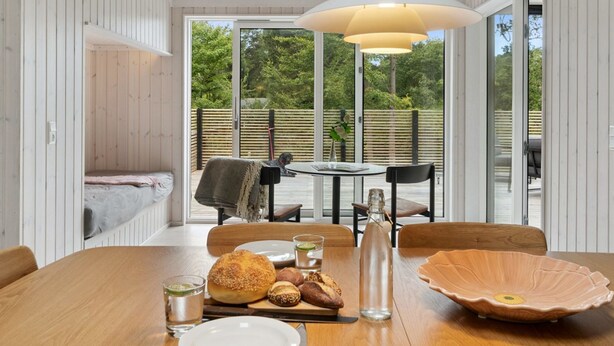 A dining area with a wooden table, chairs, and a large window. - "Aggi" - 850m from the sea by Interhome (Fårevejle)