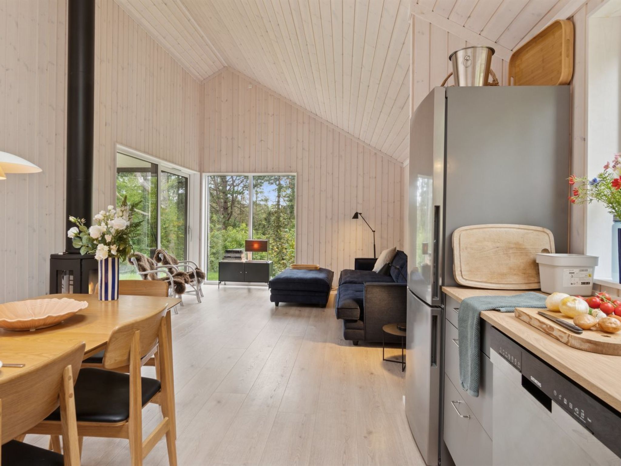 A modern kitchen with a built-in refrigerator, wooden cabinets, and a dining area with a table and chairs.