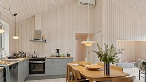 A modern kitchen with wooden paneling, a dining area with a wooden table and chairs, and a built-in oven. - "Aggi" - 850m from the sea by Interhome (Fårevejle)