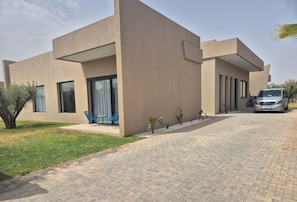 A modern house with a paved driveway and a parked car. - Magnificent Villa By K&L (Marrakech)