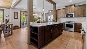 Une cuisine moderne avec des meubles en bois, des appareils électroménagers en acier inoxydable et des luminaires suspendus.