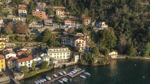 A coastal town with buildings along the waterfront, a marina with several boats, and a hillside with residential and commercial structures. - Villa Silva wiht pool - My Rental Homes (Torno)