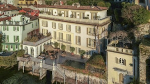 A multi-story building with a central courtyard, balconies, and a stone staircase leading to a dock. - Villa Silva wiht pool - My Rental Homes (Torno)