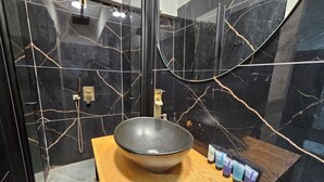 A bathroom with a black marble sink, a wooden vanity, and a glass shower enclosure. - Lovely studio with AC in Haifa (Haifa)