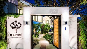 The entrance to a hotel with a white facade, a logo with a stylized tree, and a pathway leading to the interior. - Maitri ❤️ 2 BR | 3 BA | Private Pool | Villa | Fast Wifi (Tamarindo)