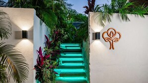 A staircase with green lighting, surrounded by lush tropical plants, and a decorative wall art piece. - Maitri ❤️ 2 BR | 3 BA | Private Pool | Villa | Fast Wifi (Tamarindo)