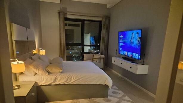 Habitación de hotel moderna con una cama grande, televisión y vista a la ciudad desde la ventana.