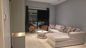 Una sala de estar moderna con un sofá gris, cojines estampados, una mesita redonda y dos sillones.