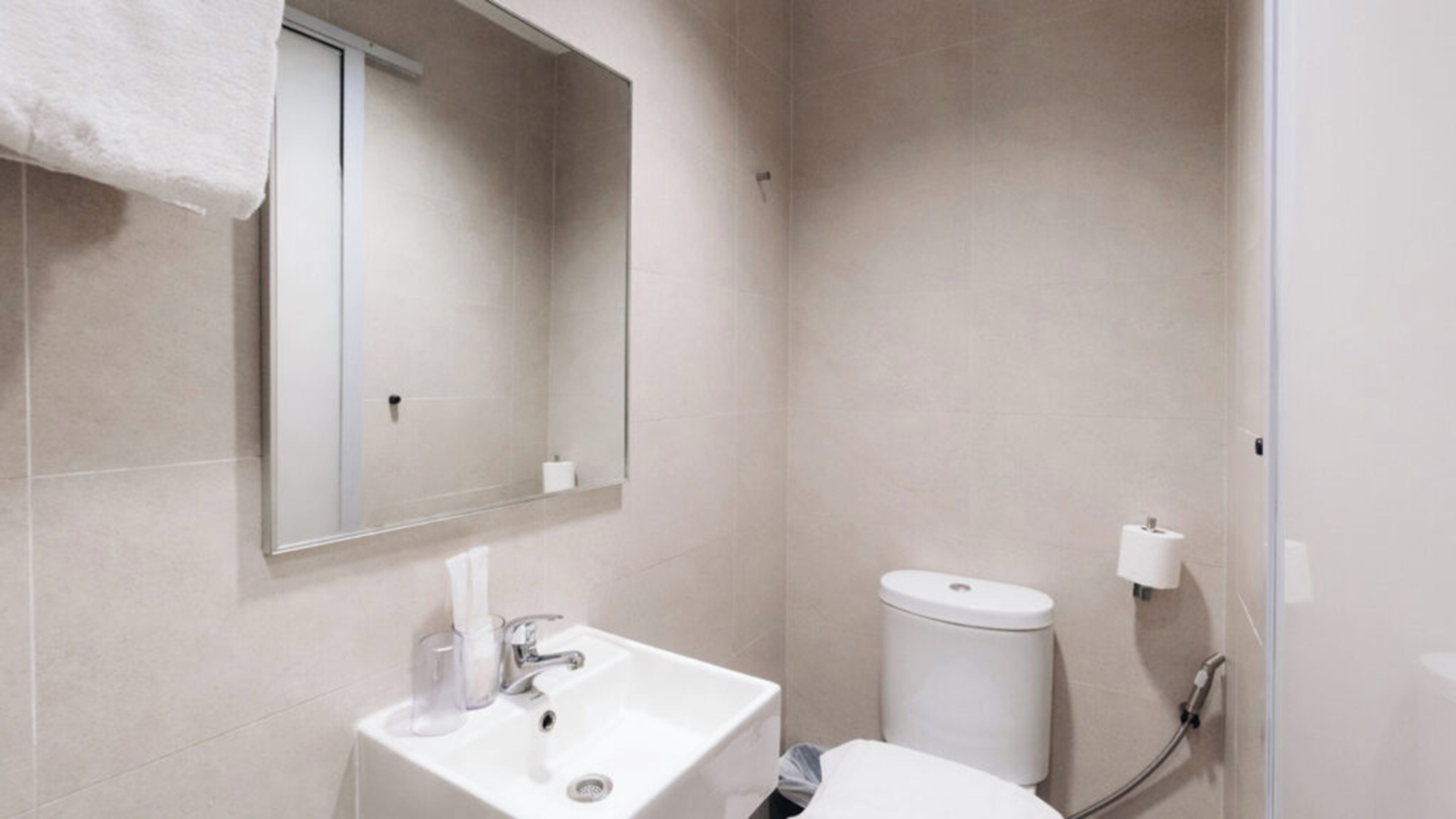 A modern bathroom with a white sink, mirror, and toilet.