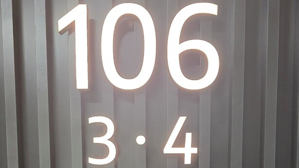 Een muur met verticale lijnen en verlichte cijfers '106' en '3,4'.