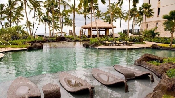 A swimming pool with lounge chairs, palm trees, and a building in the background. - Stunning Ocean View Luxury Suite - Ko Olina Beach Villas O421 End Unit (Kapolei)