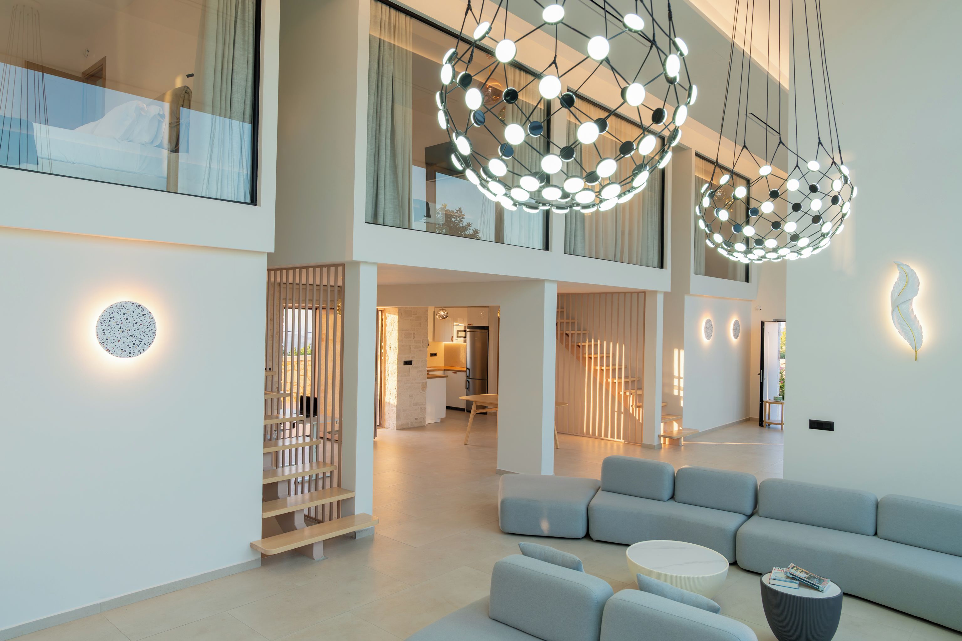 A spacious living area with a modern design, featuring a large grey sofa, a coffee table, and a unique spherical light fixture.