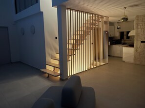A modern interior with a staircase, a kitchen area, and a seating area.