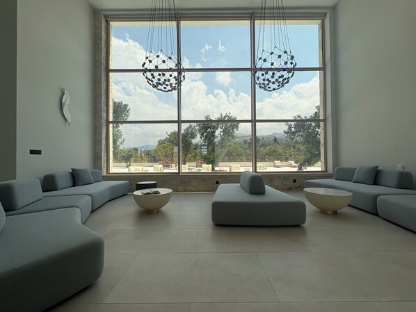 A modern living room with a large window, grey sofas, and a central coffee table.