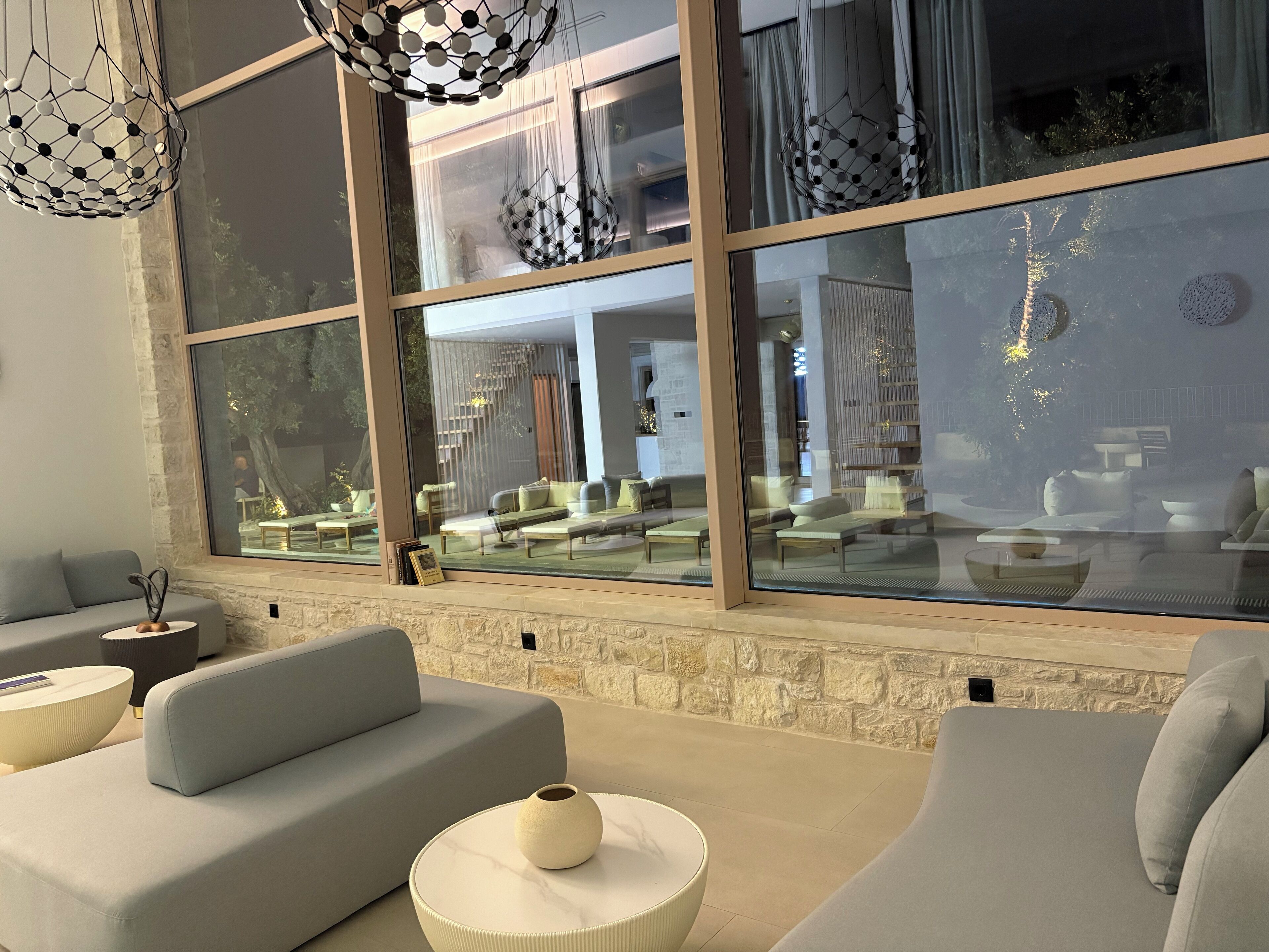 A modern living room with a large window, stone wall, and contemporary furniture.