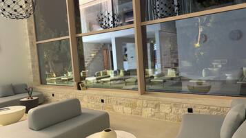A modern living room with a large window, stone wall, and contemporary furniture.